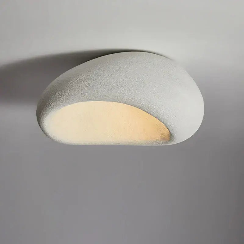 A sleek matte cream ceiling chandelier shaped like gray stone with warm curved interior glow for bedroom lighting