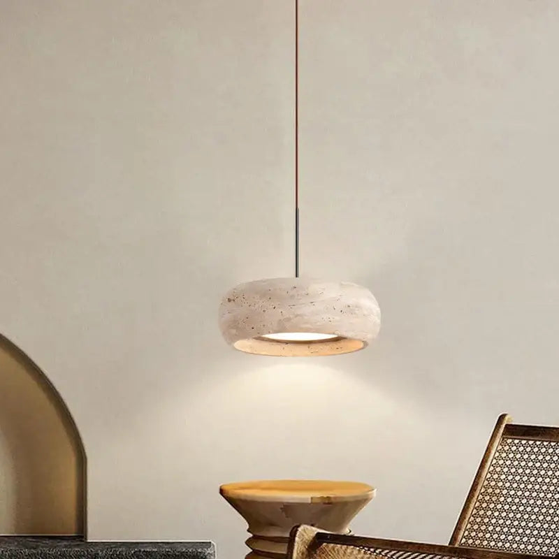 Wabi-sabi off-white stone pendant light with textured concrete shade and slender metallic rod for dining room use