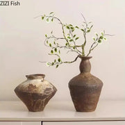 Rustic brown decorbites ceramic vase with textured earthy surface and slender neck holding delicate green branches for living room decor
