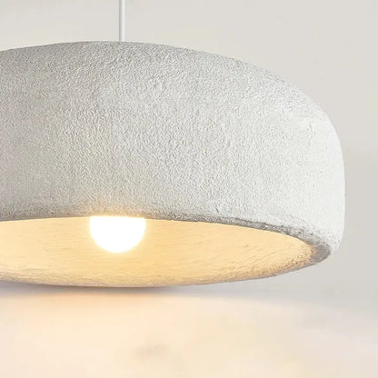 Wabi sabi textured white ceramic led pendant light with a dome shape providing a warm glow for dining room use