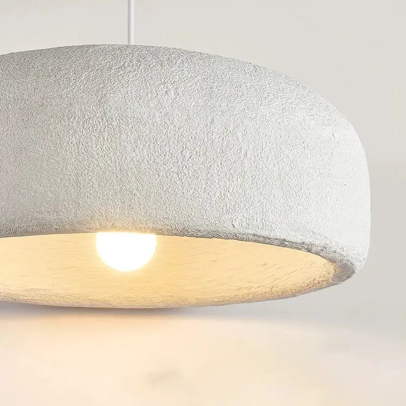 Wabi sabi textured white ceramic led pendant light with a dome shape providing a warm glow for dining room use