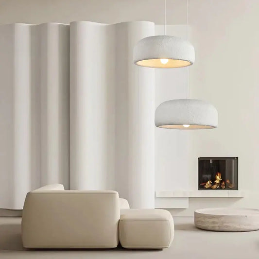 Two modern wabi sabi textured white ceramic led pendant lights hang emitting a warm glow for dining room use
