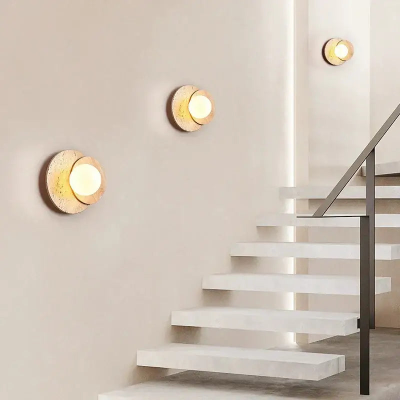 Gold-toned circular wall lamp with textured stone-like finish and warm light for decorbites cream style bedroom decor