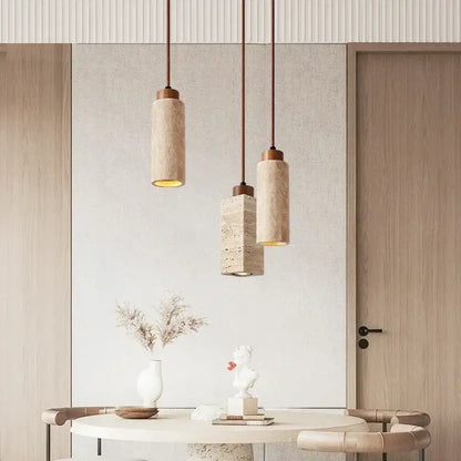 Three modern pendant lights with yellow marble stone shades and brass hardware hang above a minimalist dining table