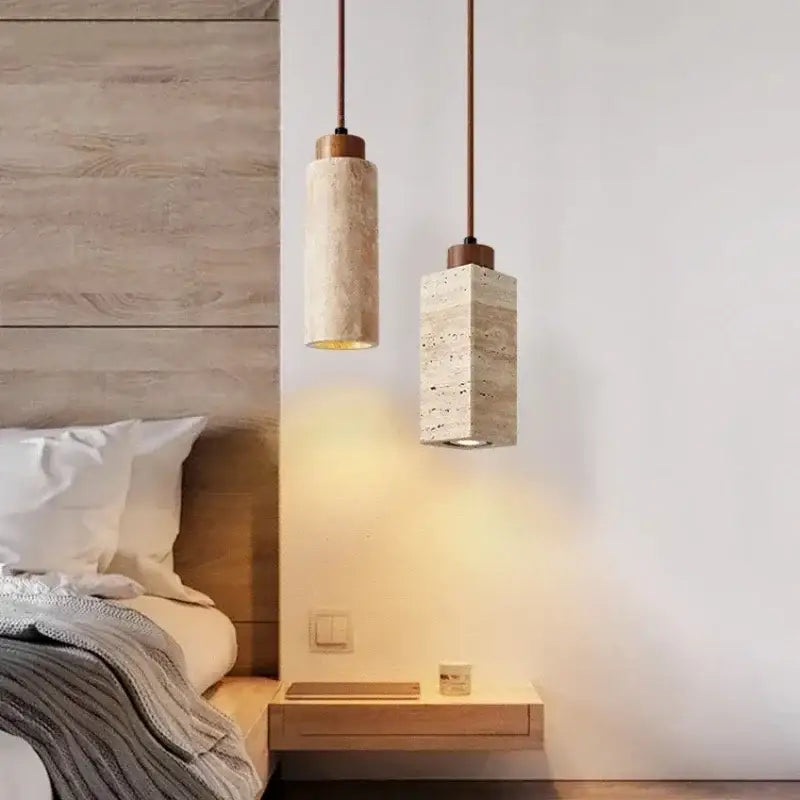 Two minimalist wabi-sabi pendant lights with yellow marble stone shades and brass cord pendants above a nightstand