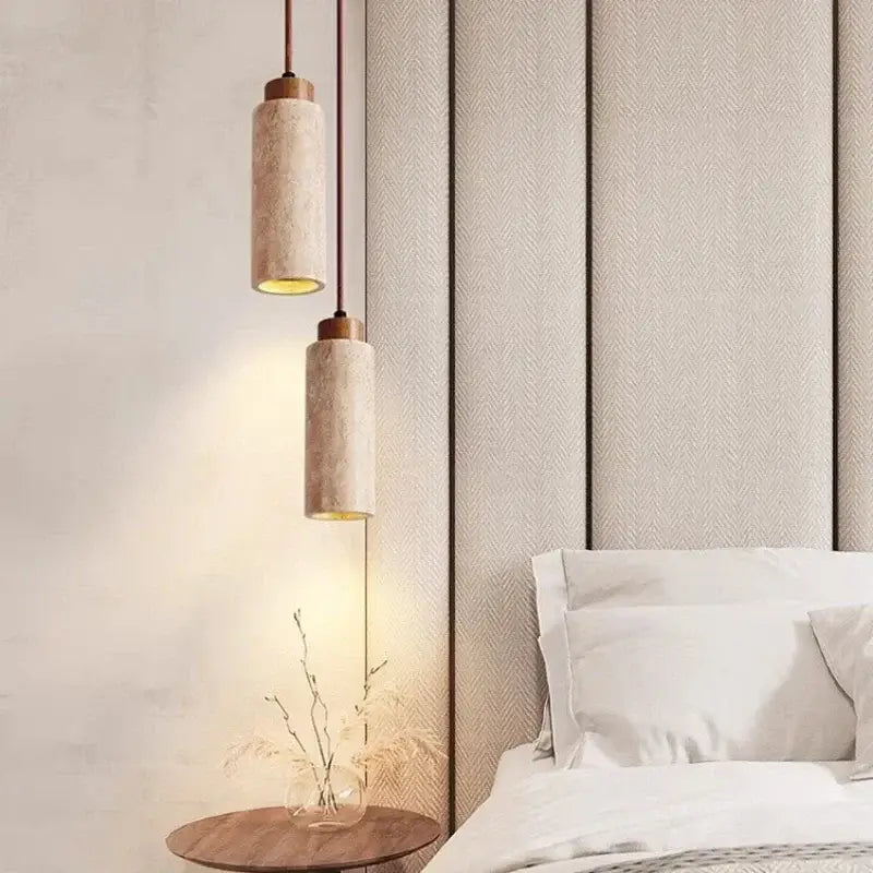 Two cylindrical pendant lights with beige concrete shades and brass accents for modern interiors and bedroom use