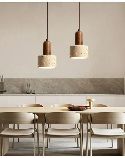 Two minimalist wabi sabi yellow stone pendant lights with cylindrical concrete shades hang above dining table