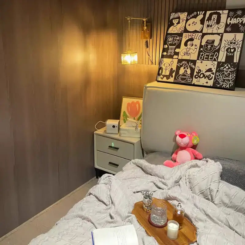Pink plush stuffed bear on a bed beside a walnut and brass cube glass led wall sconce by decorbites cube glass in bedroom decor