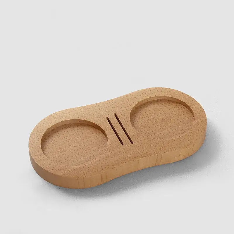 Light brown walnut and oak wooden tamping station with two circular indentations and central slit for espresso tamper decorbites