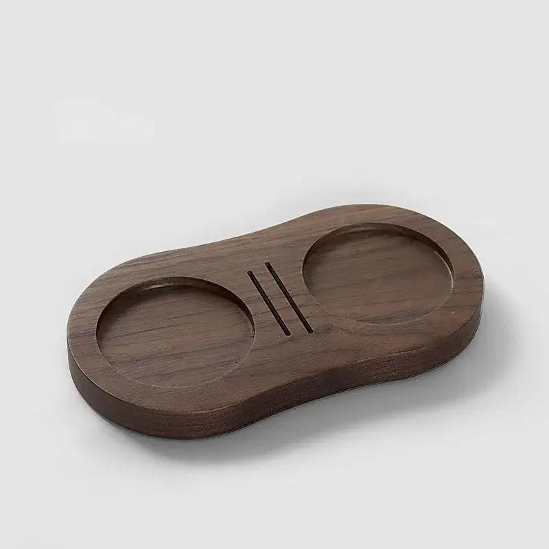 Dark brown walnut and oak wooden tamping station with two circular indentations and central slit for espresso tamper use