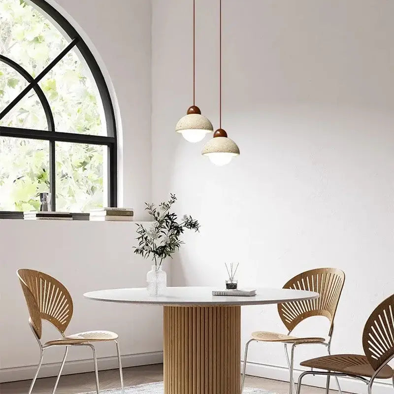 Two off-white textured ceramic cave stone pendant lights with copper fixtures hang in a dining room decorbites cave stone decor