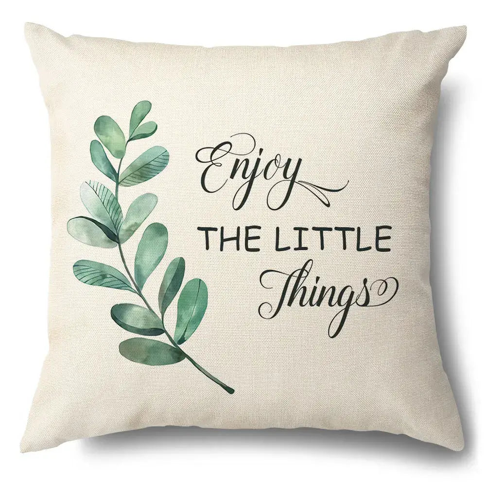 Beige linen pillow case with watercolor green leaves decorative design and enjoy the little things cursive script