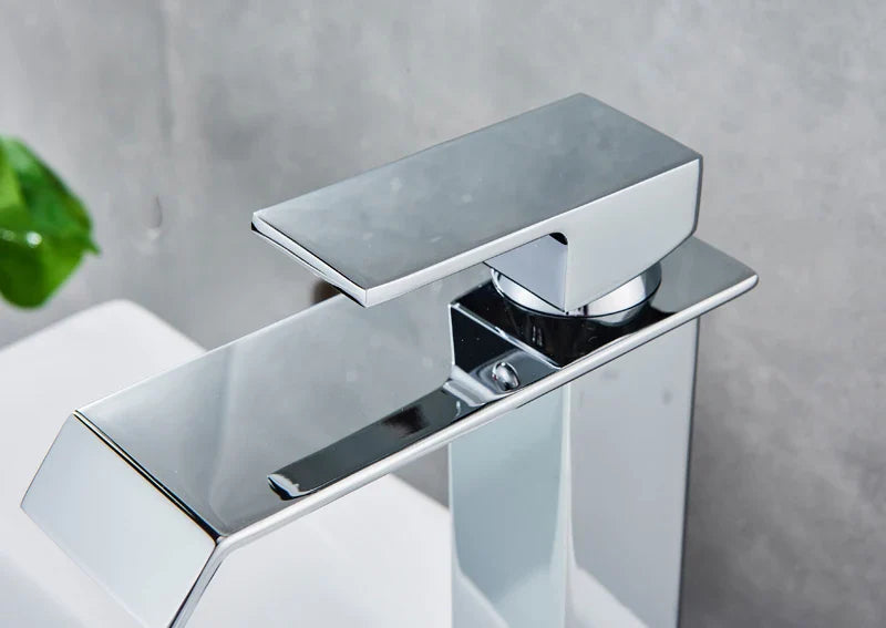 Modern chrome-finished waterfall bathroom faucet with a sleek angular design and rectangular spout for single hole installation