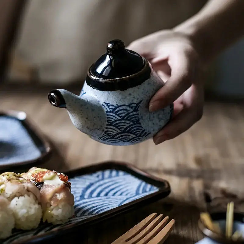 A small ceramic teapot with speckled white body and blue wave patterns in the decorbites blue ceramics kitchen seasoning set