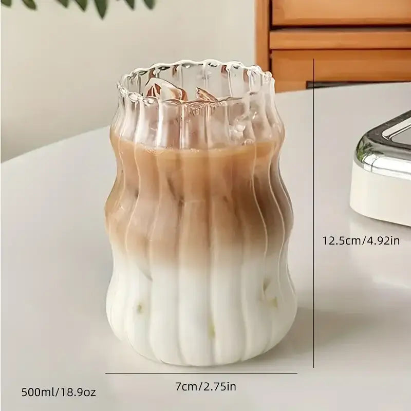 A clear wavy ribbed glass cup 500ml ins glass tumbler with fluted rim containing gradient iced coffee
