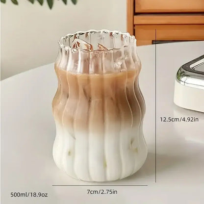 A clear wavy ribbed glass cup 500ml ins glass tumbler with fluted rim containing gradient iced coffee