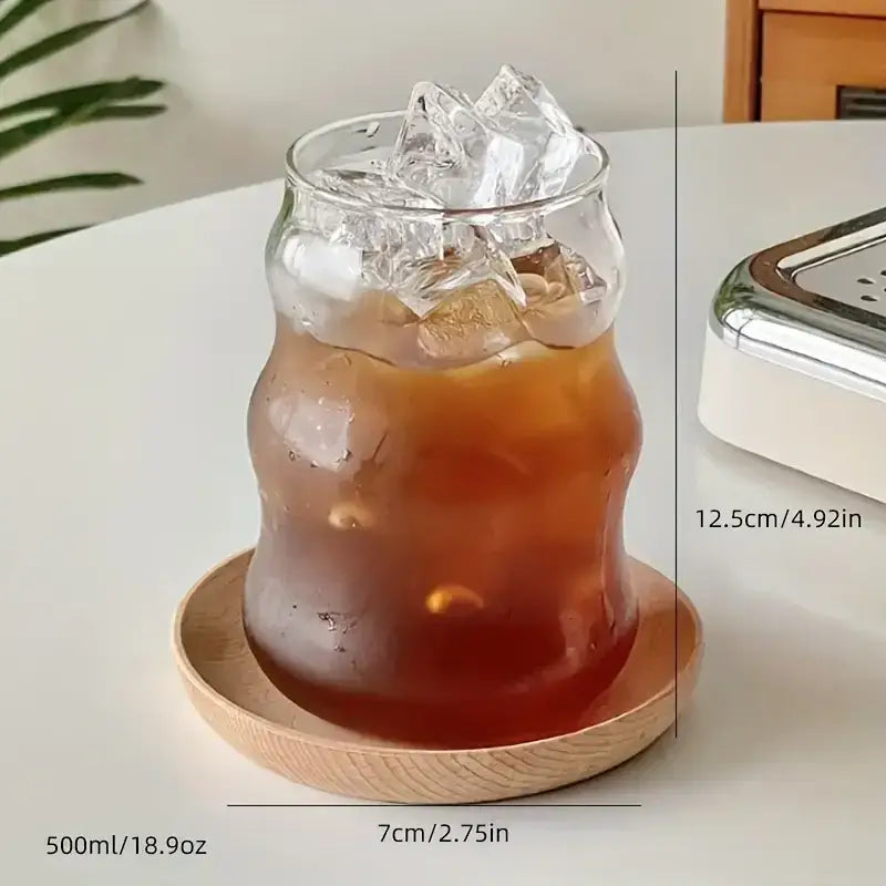 A clear wavy ribbed glass cup 500ml ins glass filled with iced coffee on a wooden coaster