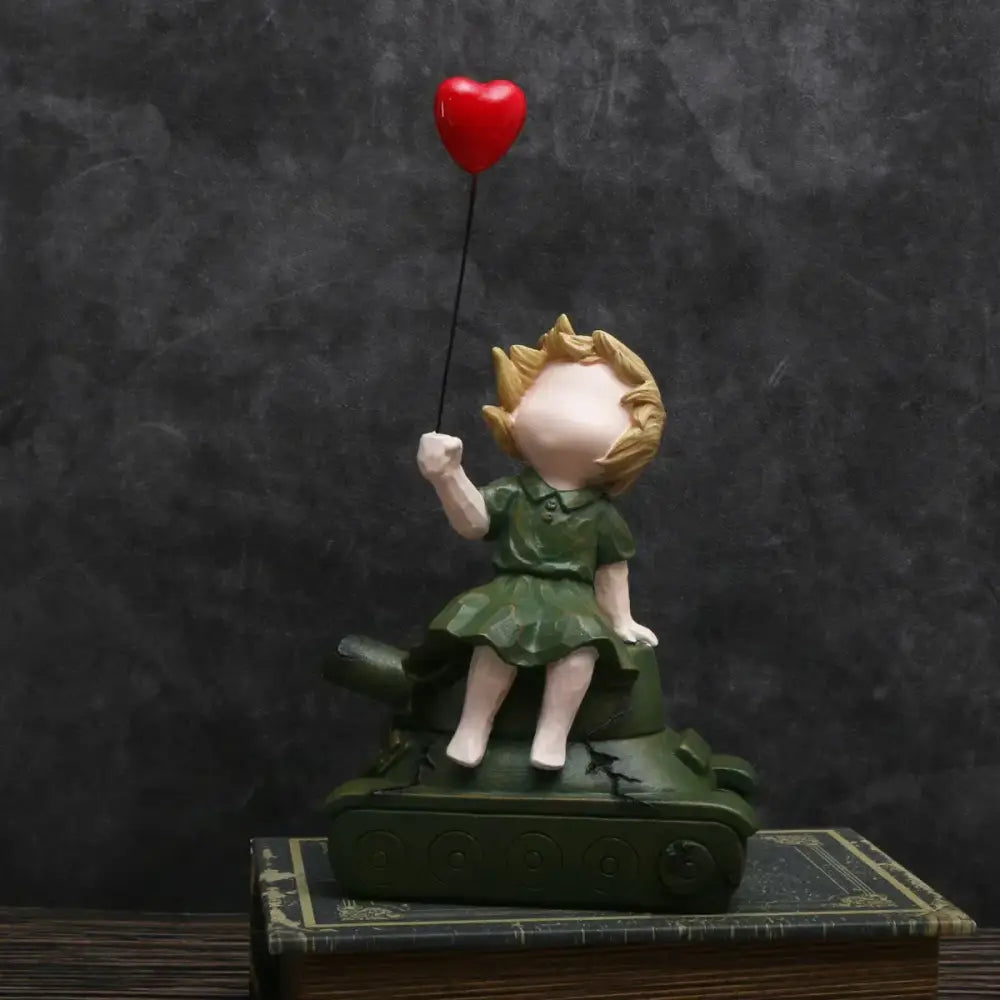 A resin balloon girl tank statue featuring a blonde girl in green dress holding a red heart balloon for living room decor