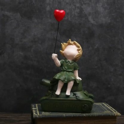 A resin balloon girl tank statue featuring a blonde girl in green dress holding a red heart balloon for living room decor