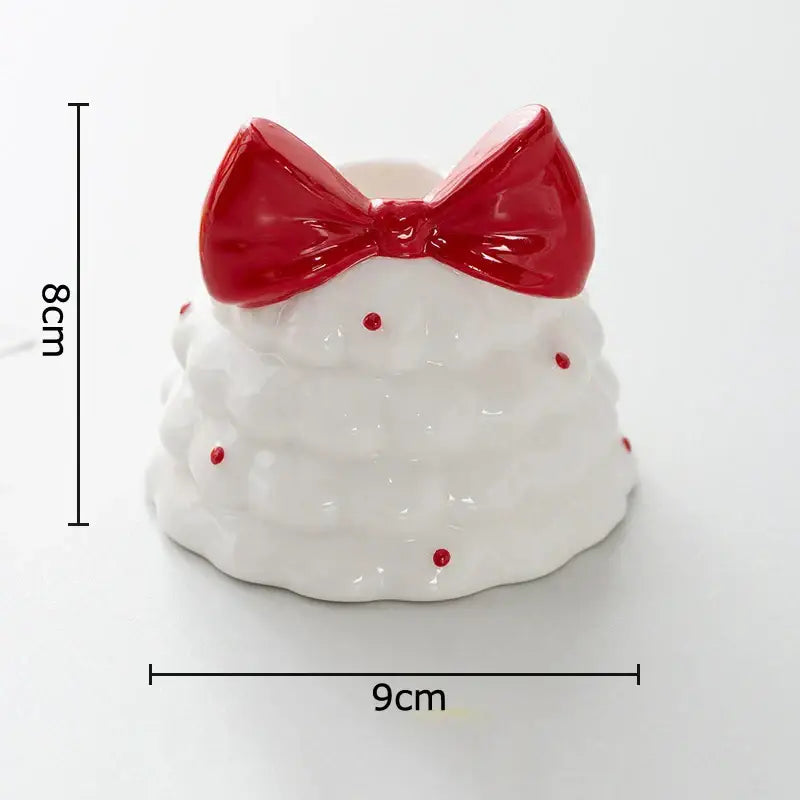 A glossy white ceramic candle holder shaped like a tiered cake with red polka dots topped with a red bowknot tree decorbites bowknot tree