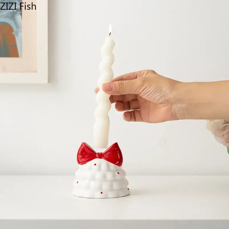 White ceramic candle holder with red bow and dotted texture holding twisted white taper candle by decorbites bowknot tree