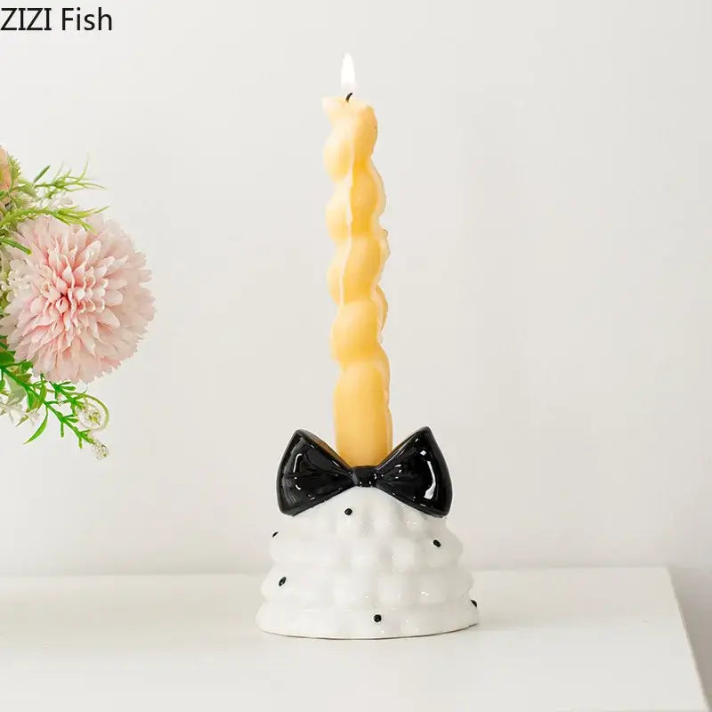 White ceramic candle holder with black polka dots and glossy black bowknot tree design holding twisted yellow candle decorbites bowknot tree