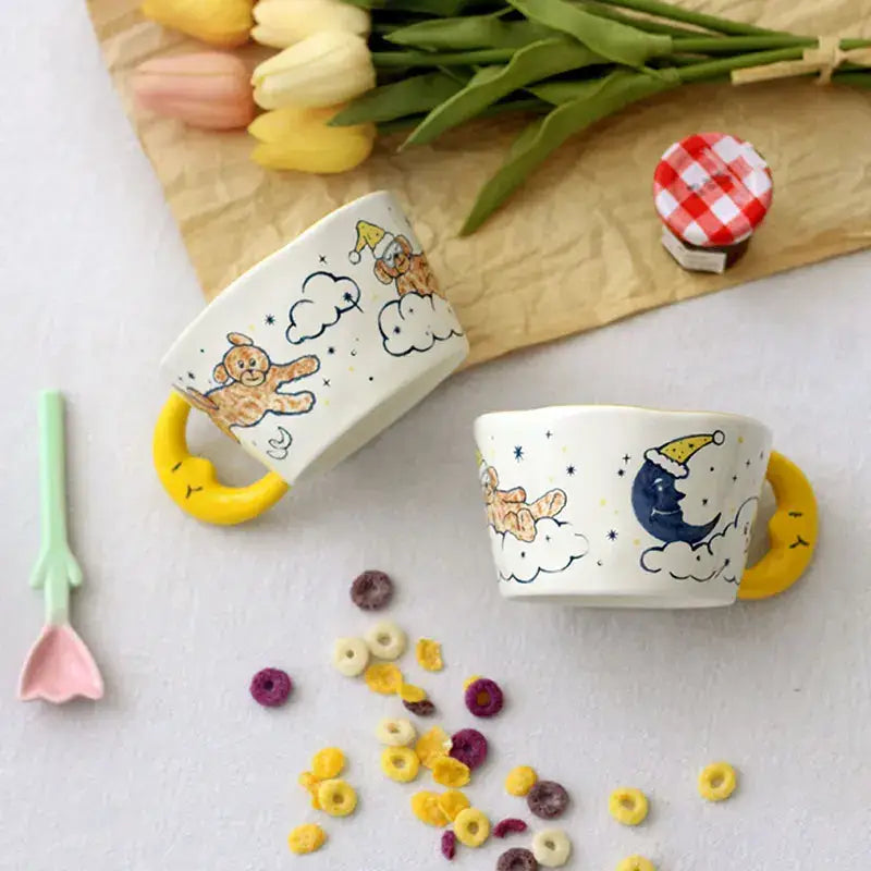 Off-white bear moon ceramic mug with yellow crescent moon handle featuring cartoon bear in santa hat design