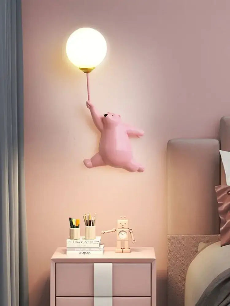 Pink polar bear kids wall lamp holding a warm-toned round bulb as part of whimsical wall lamp set for bedroom