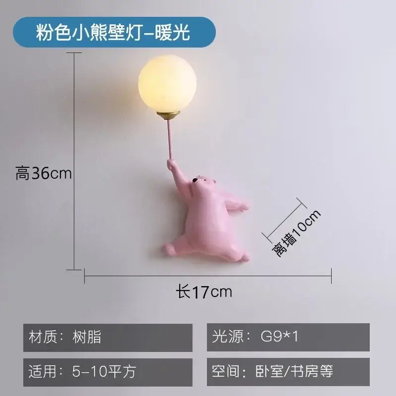 Whimsical pink resin bear kids wall lamp holding a glowing bulb in a kids wall lamp set for bedroom