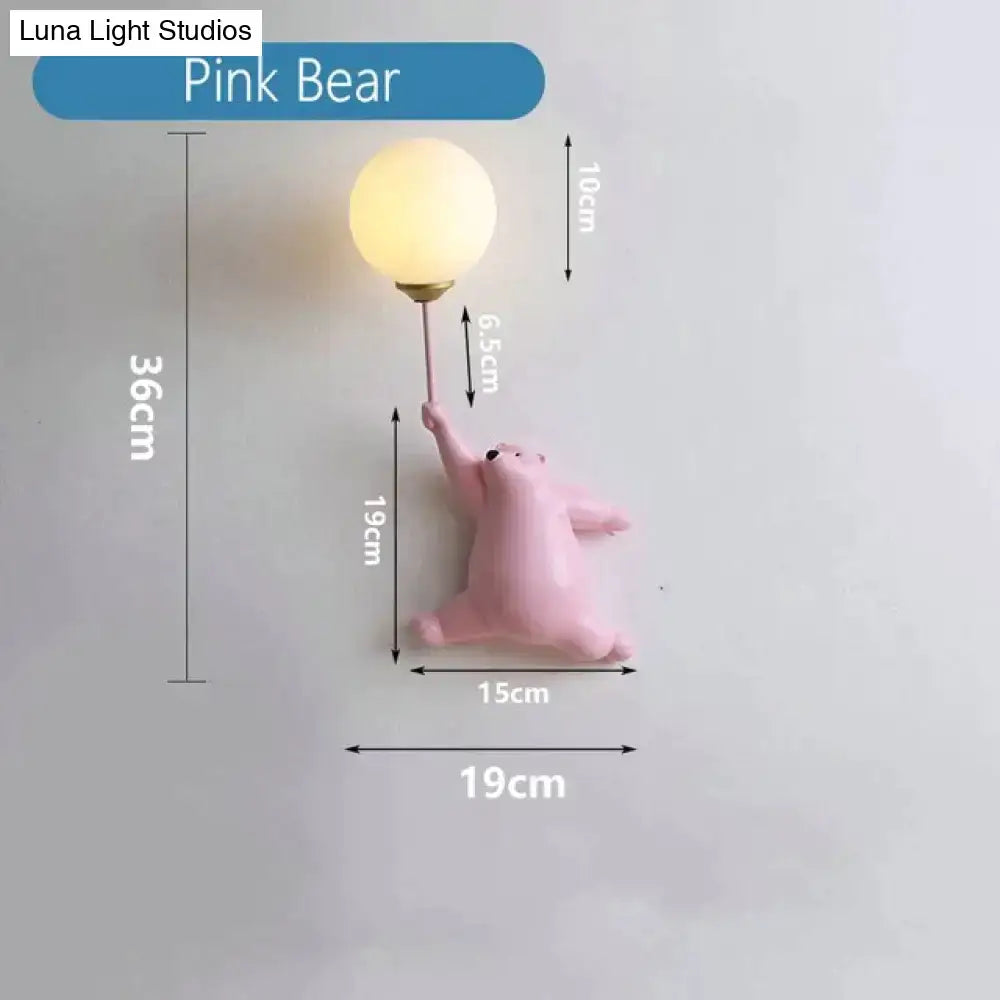 Whimsical pink polka dot girl wall lamp with a matte pink bear holding a frosted glass bulb on a slender metallic stem