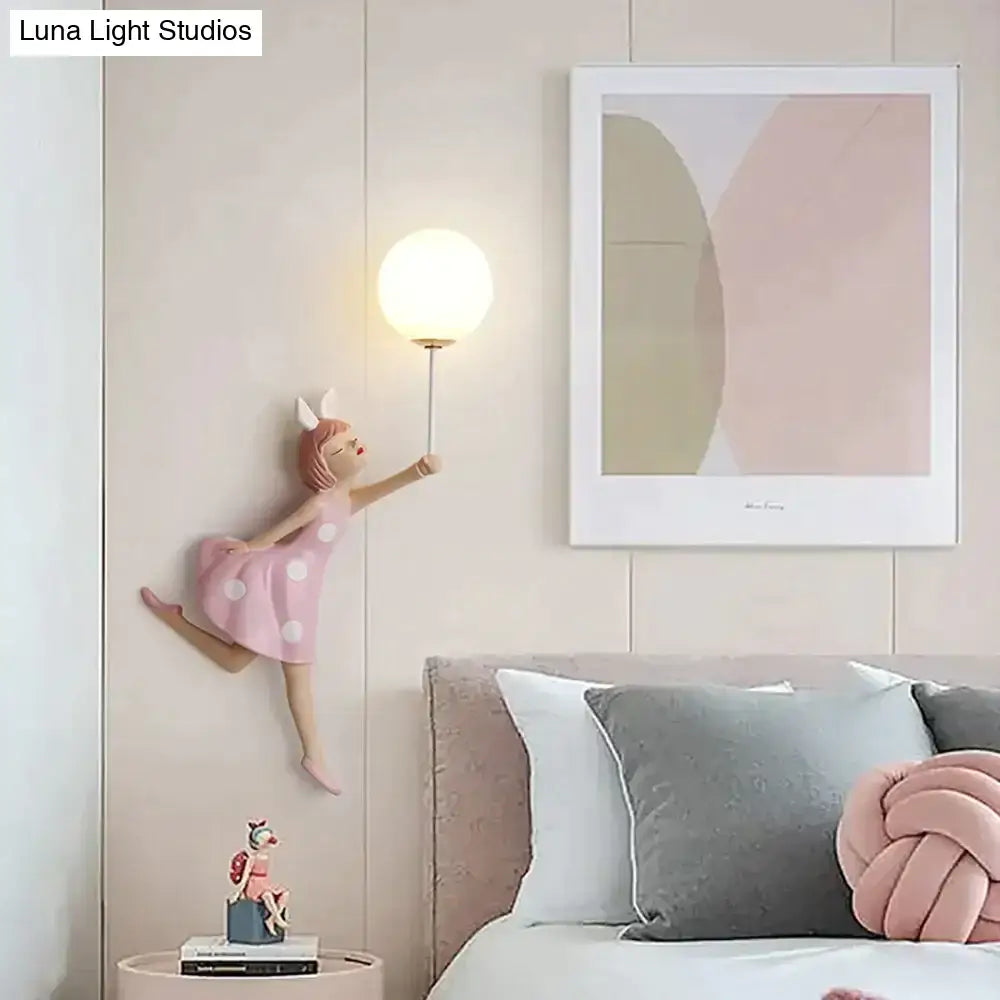 Whimsical pink polka dot fairy girl wall lamp holding a spherical light for bedroom decoration and ambiance