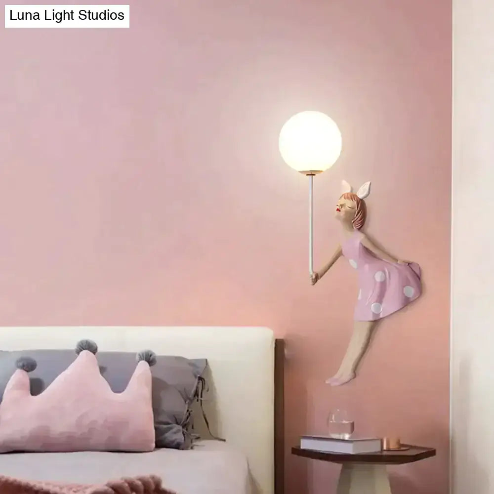 Whimsical pink polka dot porcelain fairy girl wall lamp featuring a glowing bulb on a slender stem for bedroom use