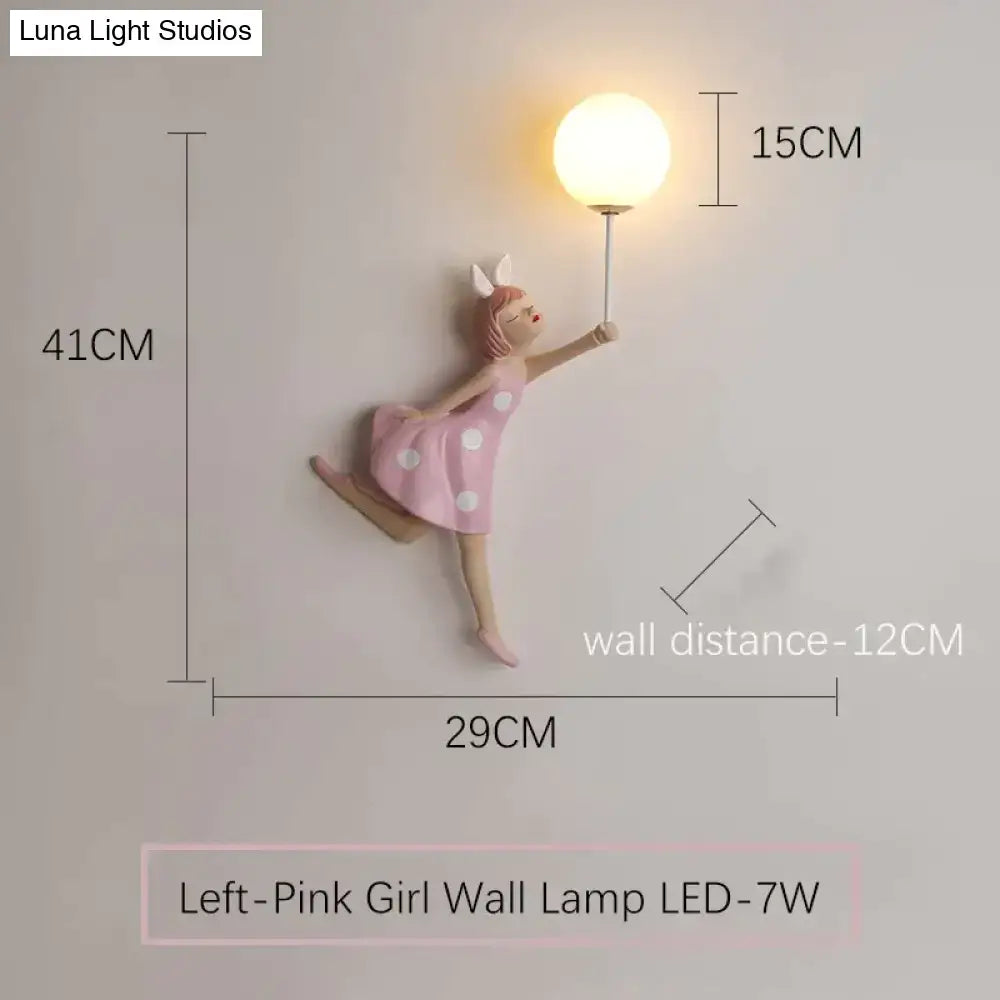 Whimsical pink girl wall lamp with white polka dots featuring a dancing figure holding an illuminated globe bulb