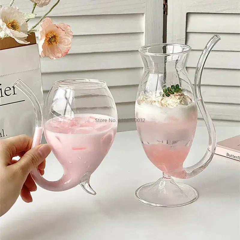Clear glass vampire cocktail glass cup with curved handle filled with pink liquid and ice for dining room decor