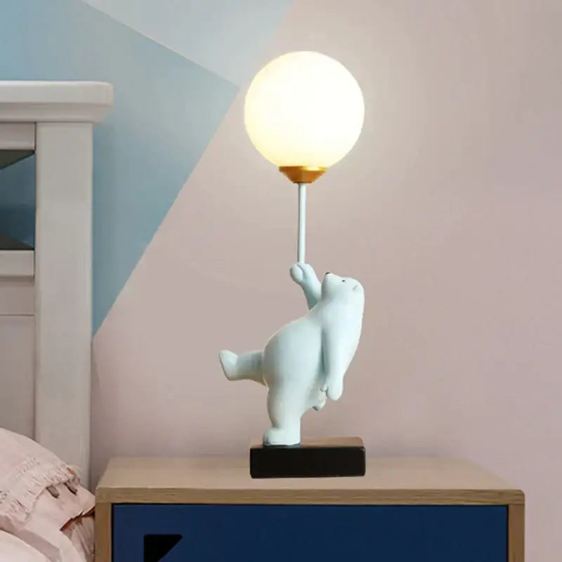 White polar bear moon lamp with spherical frosted glass bulb and gold-toned base on black pedestal for bedroom décor