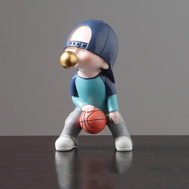 A whimsical resin boys sports statue of a child in a blue cap blowing a golden bubblegum ball holding orange basketball decorbites boys