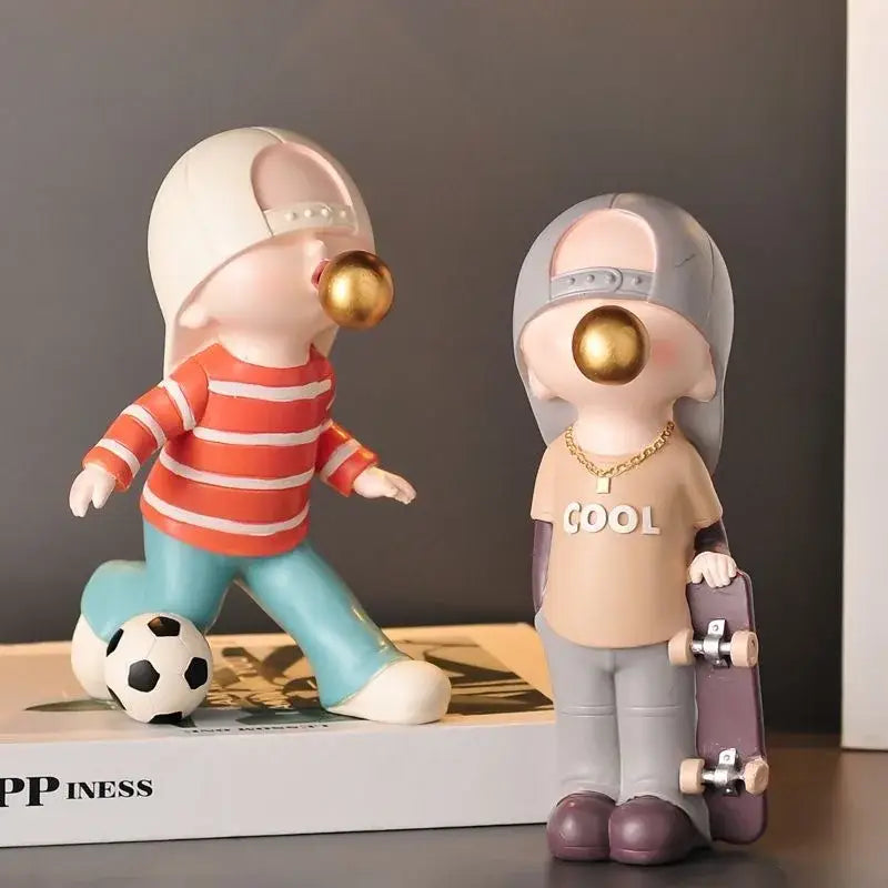 Two whimsical resin decorbites boys sports statues featuring an orange striped soccer player and beige cool tee skateboarder