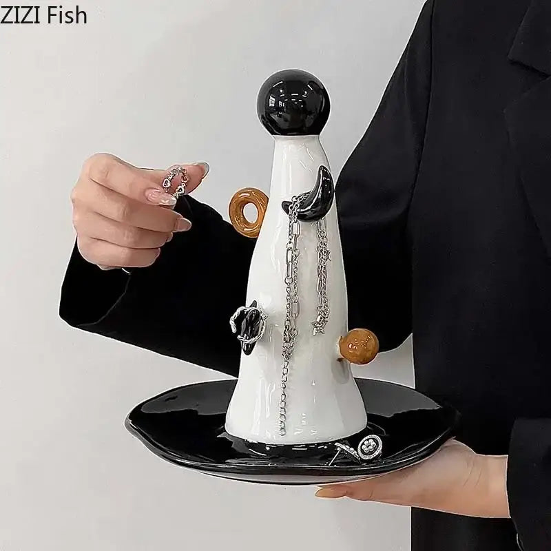 A sleek white and brown ceramic jewelry display stand with glossy black top and decorative orange accents for necklace display