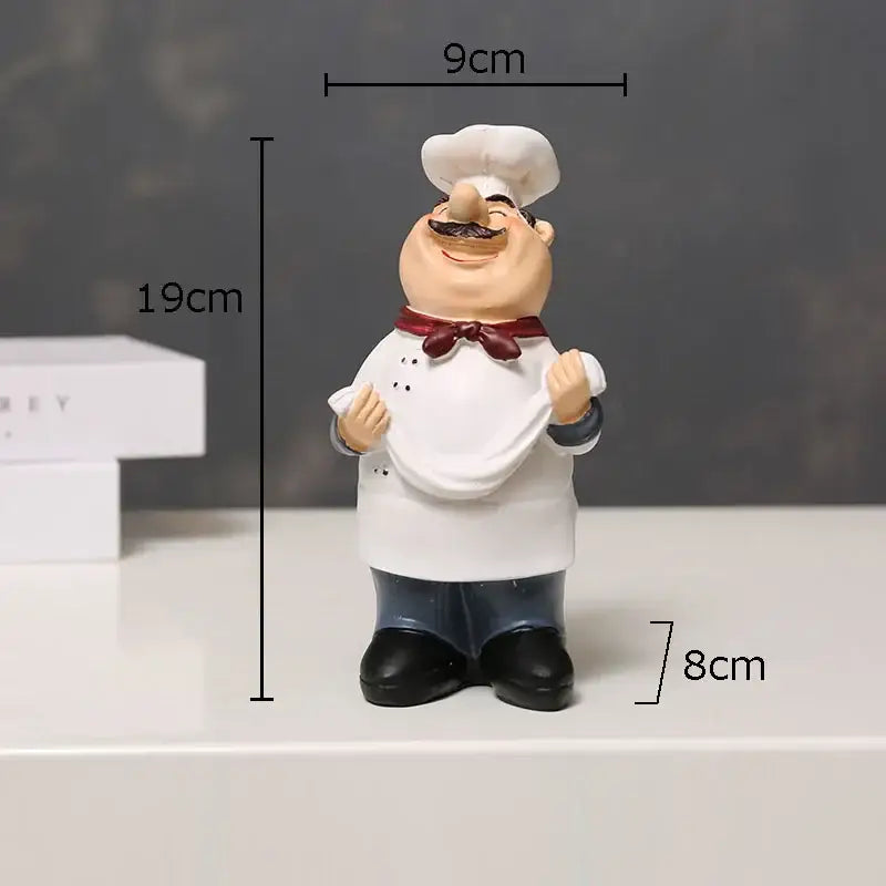 A cheerful bearded chef resin figure with white hat apron red bow tie black pants for whimsical kitchen decor