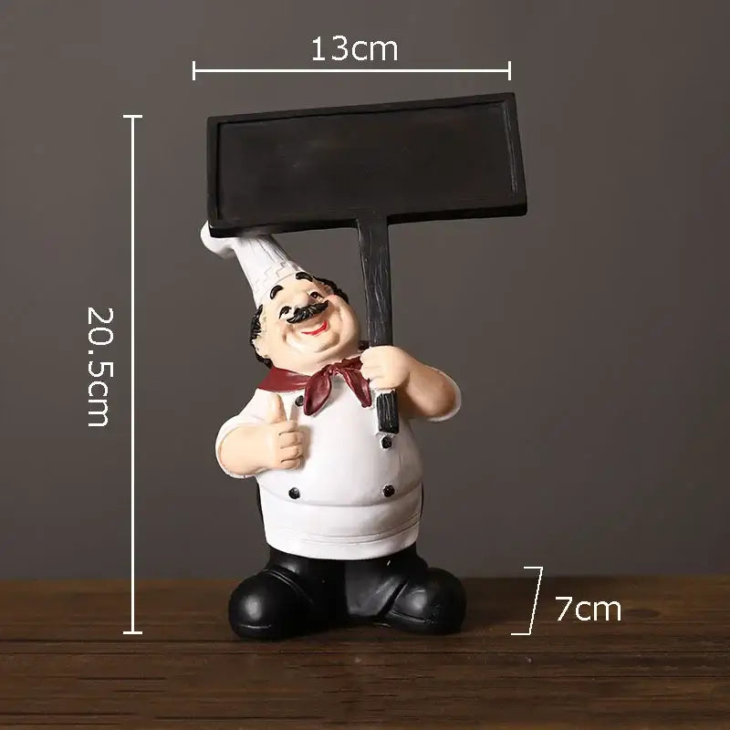 A cheerful white bearded chef resin figure in uniform holding a black chalkboard sign for kitchen decor