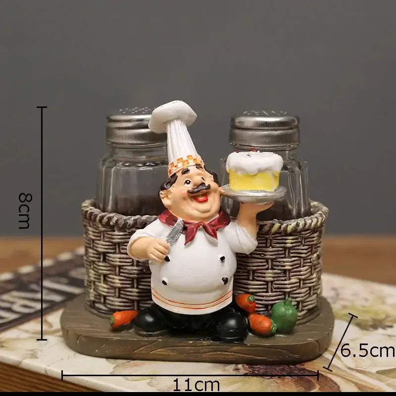 A whimsical white bearded chef resin figure in uniform holding cake slice beside salt and pepper shakers in basket base