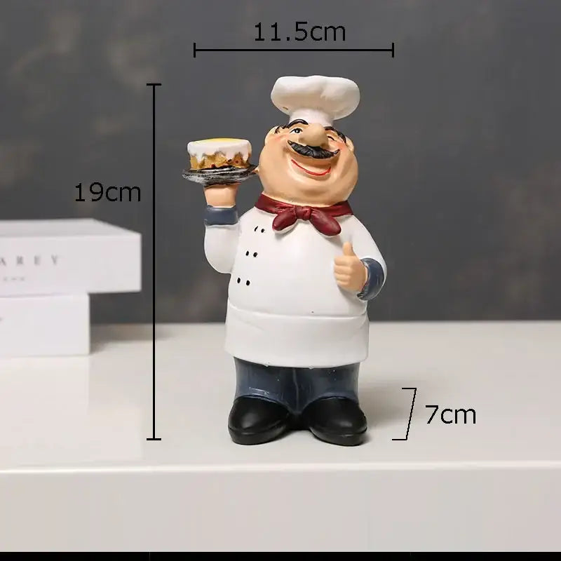 A cheerful white bearded chef resin figure with red bow tie holding a cake and giving thumbs-up kitchen decor