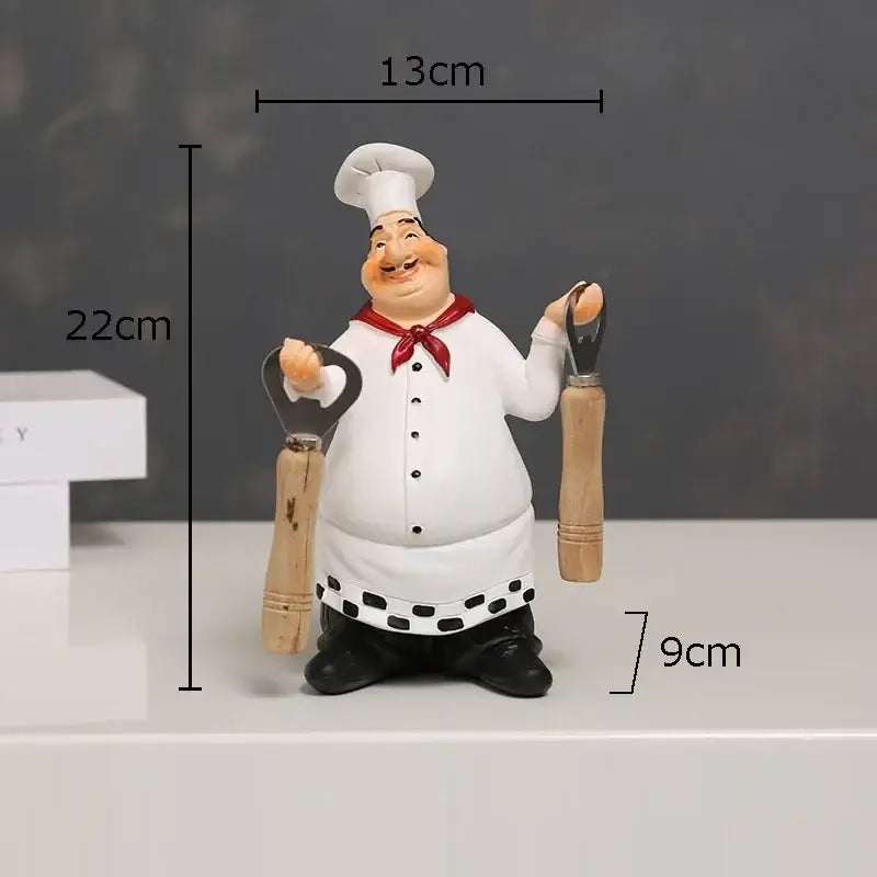 A cheerful chubby bearded chef resin figure in white uniform with red neckerchief holding wooden kitchen tools