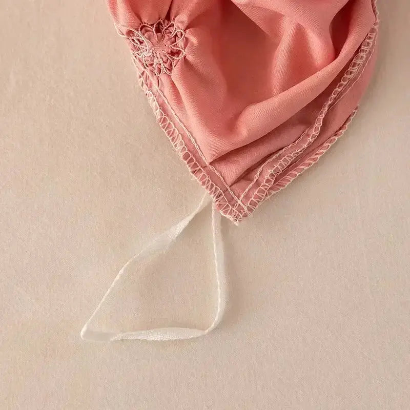 A delicate pink satin bonnet with lace trim and white ribbon tie paired with a white 3d pinch pleat duvet cover set