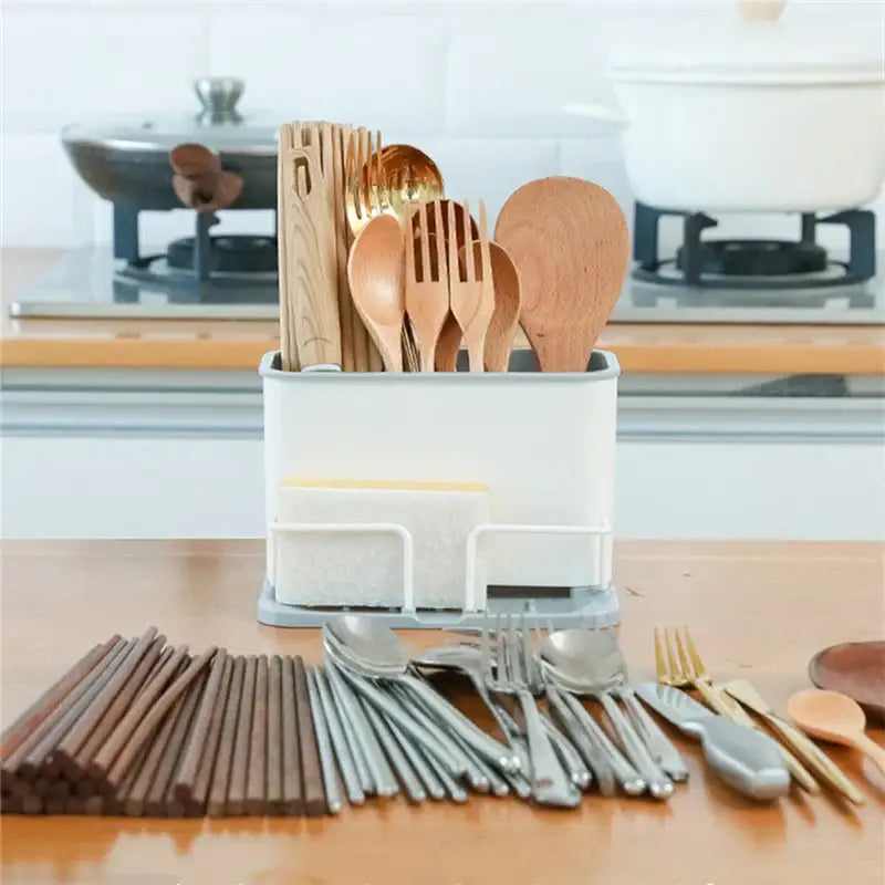 White and black double grid cutlery organizer with built-in sponge holder holding wooden spoons and ladles