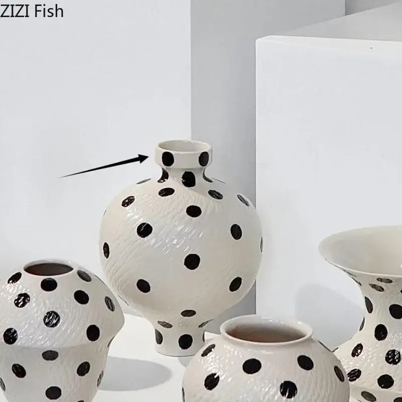 White ceramic vase with black polka dot textured surface, rounded body, and narrow neck for living room decor