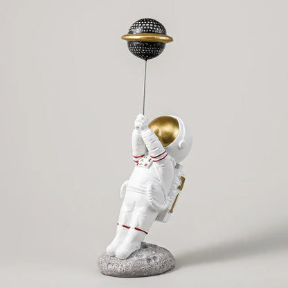 White and gold astronauts figurines holding a black dotted planet balloon for living room decor by decorbites astronauts figurines