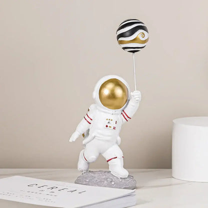 White and gold astronauts figurines with a gold helmet holding black and gold striped balloon for living room decorbites decor
