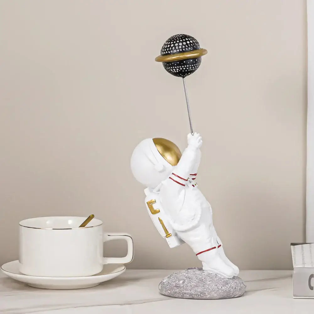 White and gold decorbites astronauts figurines holding a black dotted planet balloon for living room decor