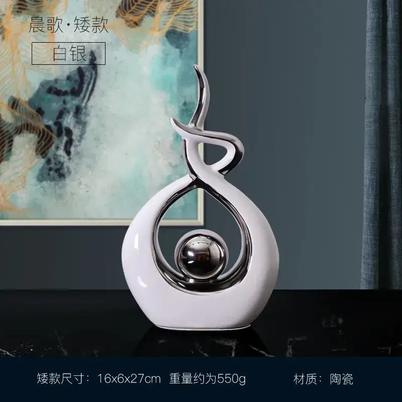 A white and gold decorbites ceramic abstract figurine set featuring a glossy swirling design with a silver sphere for living room decor